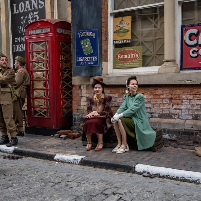 Hull High Street dress with period poster and red telephone box for filming 2 women in 1940 dress, 3 men in soldiers uniform