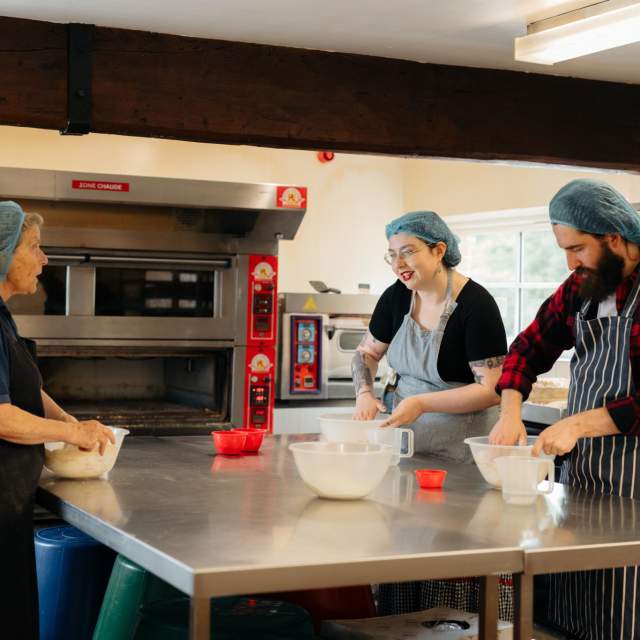 An instructor teaching visitors how to make bread at Side Oven Bakery