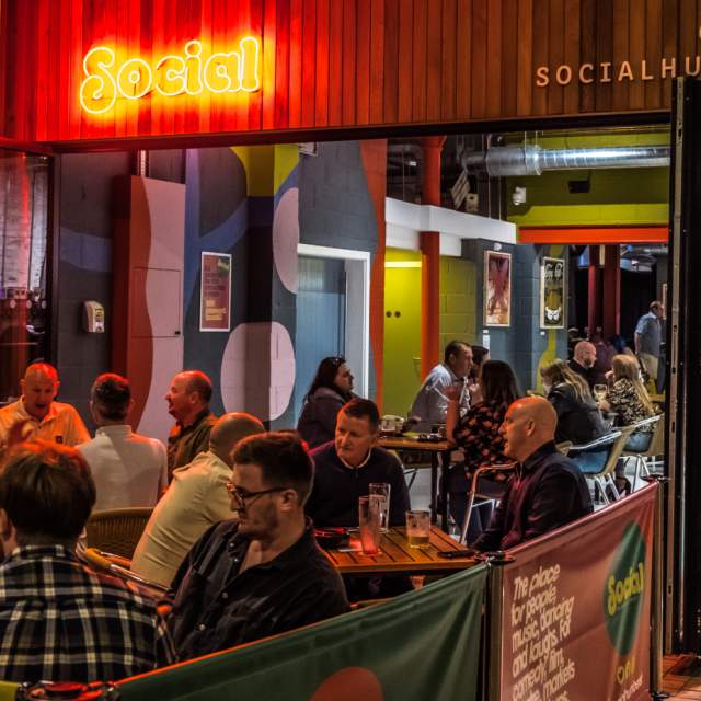 Evening scene at Social on Humber Street in Hull, with people enjoying outdoor drinks and dining under neon lighting, creating a lively atmosphere in the Fruit Market area