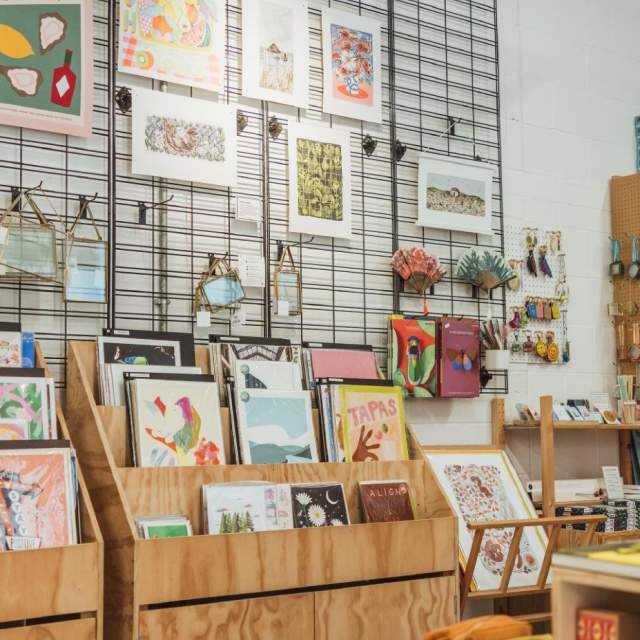 Interior of an Form Studio and studio in Hull displaying art prints, handmade gifts, stationery, books and homeware on wooden shelves and wall grids.