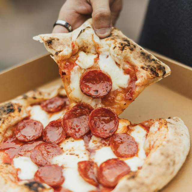 Delicious pizza being picked up from takeaway box