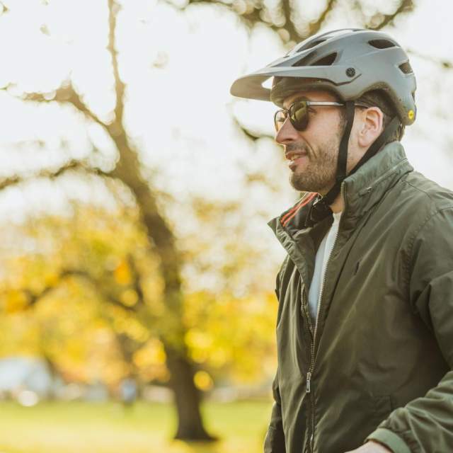 Two cyclists wearing helmets standing with their bikes on a tree‑lined path in Hull’s Pearson Park during autumn