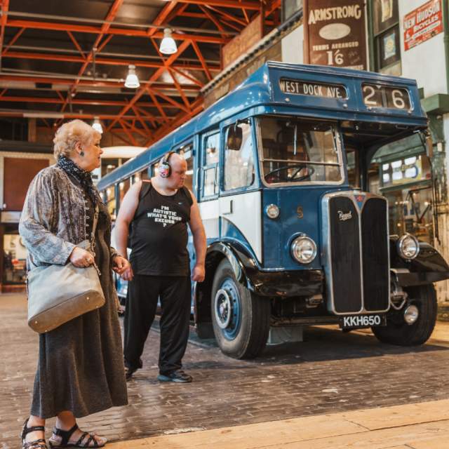 "Visitors exploring the Streetlife Museum's indoor historic street scene, featuring a vintage blue bus and step-free open exhibition space."