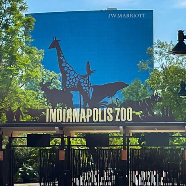 The entrance to the Indianapolis Zoo. Signage shows silhouettes of animals with the words "Indianapolis Zoo" underneath.