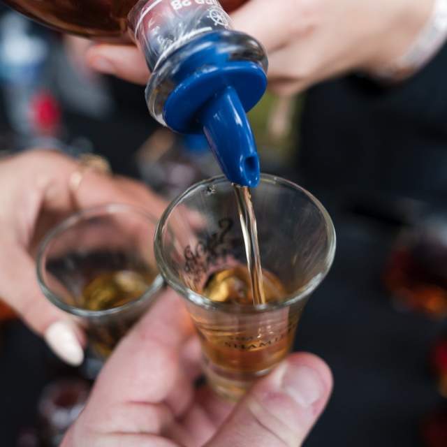 bourbon or whiskey is poured into a small shot glass