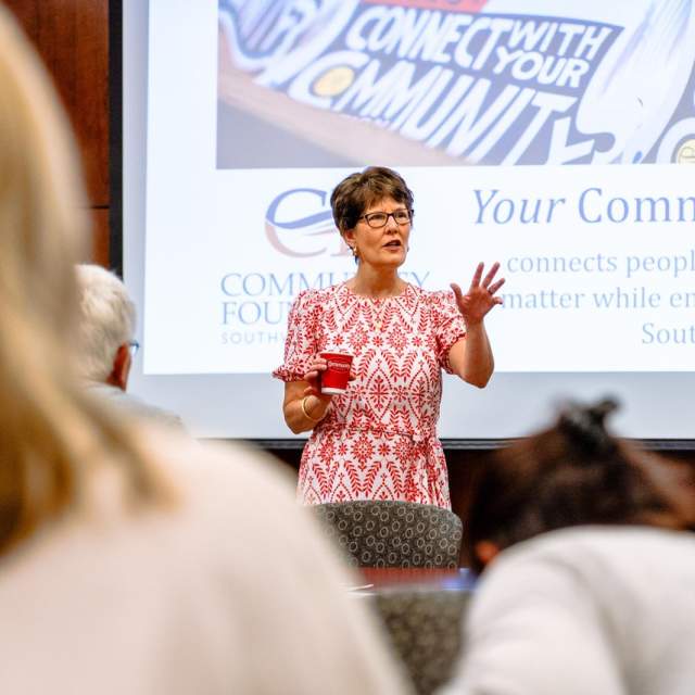 woman stands in front of projector discussing the Community Foundation