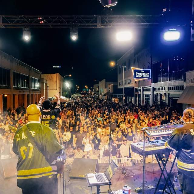 two musicians in black jerseys play guitar and keyboard on stage to screaming fans in downtown lake charles at Chuck Fest