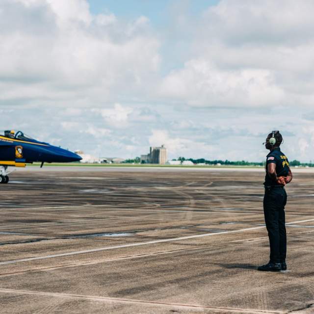 Blue Angels plane on runway at Chennault. An air traffic controller standing near the plane