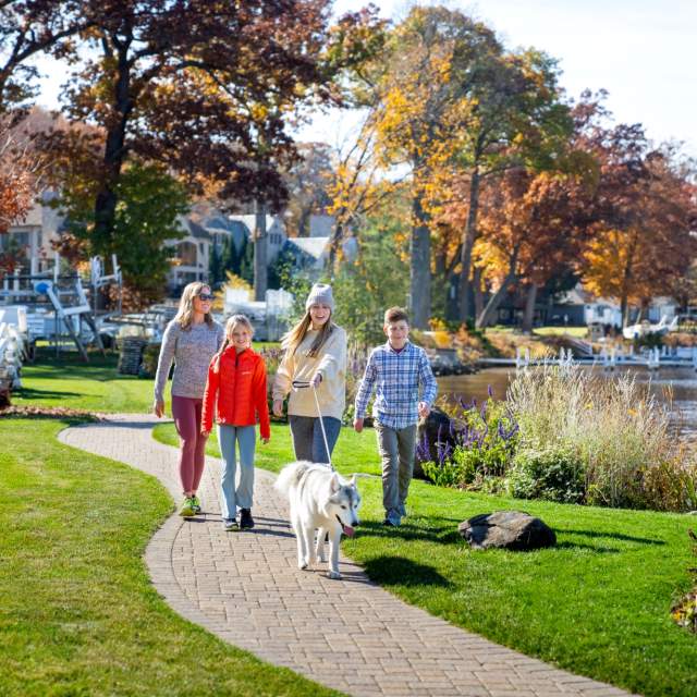 Family walking the shore path in the fall with their dog.