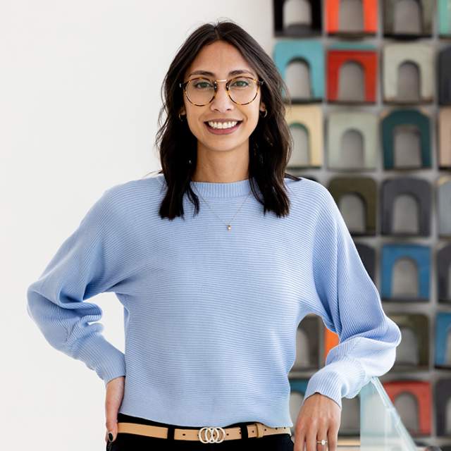 A woman standing in front of a colorful background.