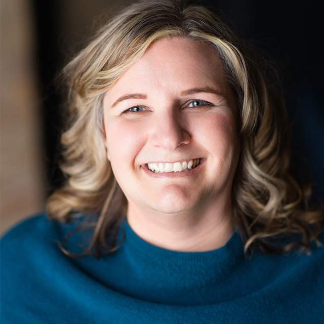 A white woman with light hair wearing a blue sweater.