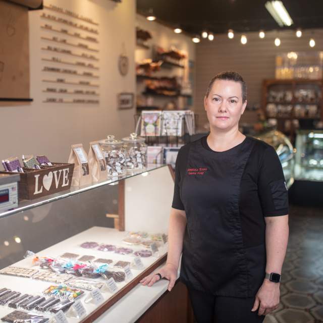 woman in a black apron standing in front of a candy case