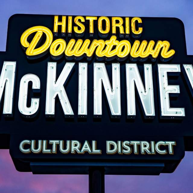 downtown McKinney neon sign with purple and blue sky