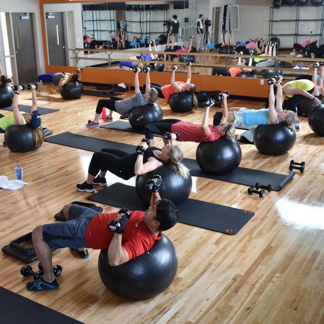People exercising on yoga balls with weights at the Apex Centre