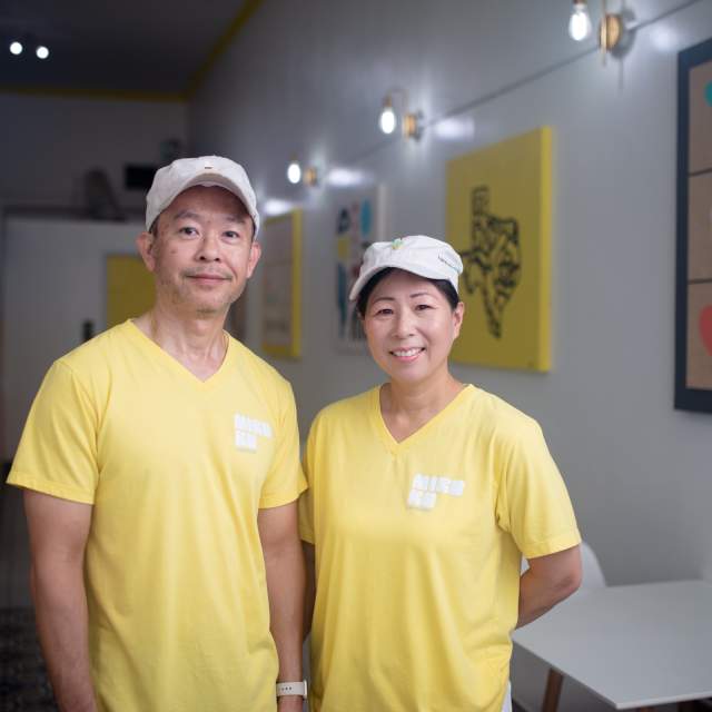 Asian couple in white ball caps and yellow shirts