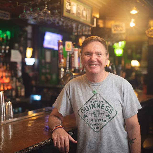 Smiling man wearing a gray Guinness tshirt