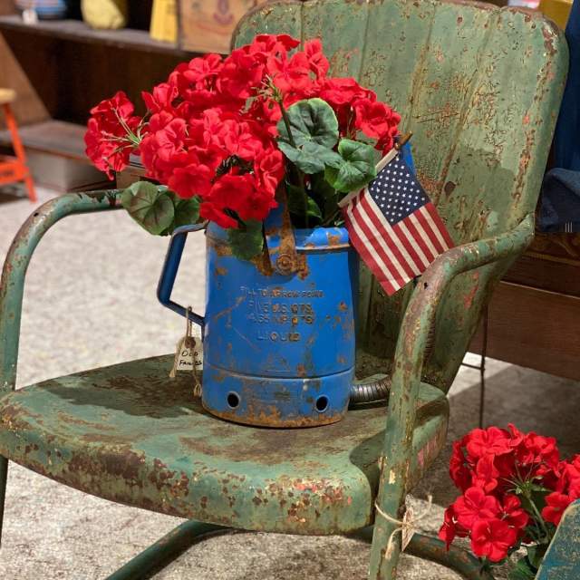 Old metal chairs with red geraniums at antique store