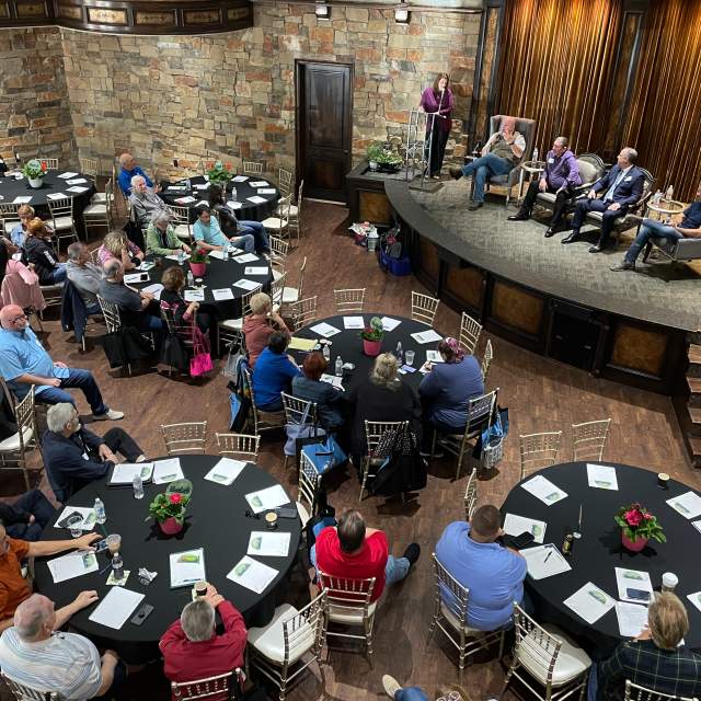Small meeting at The Sanctuary, speakers on stage, audience at round tables