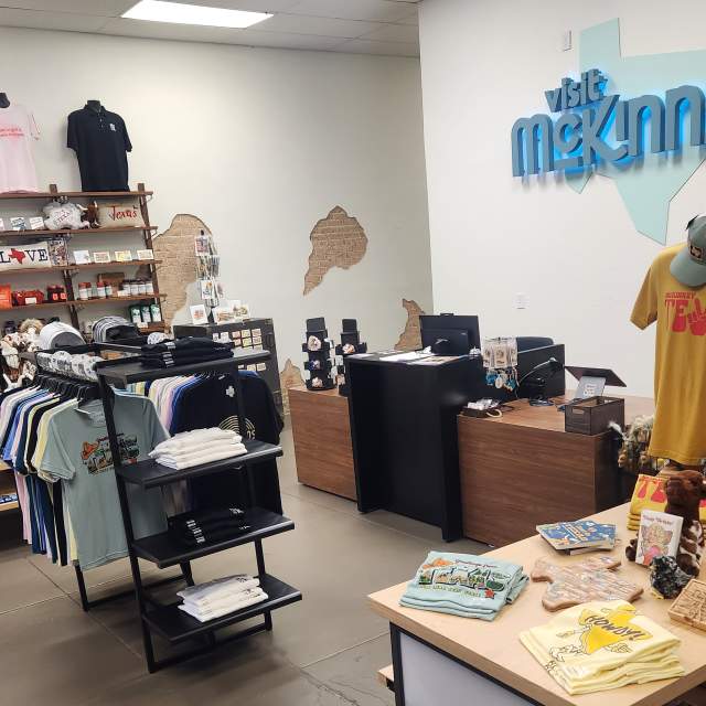 picture of shelves and merchandise - tee shirts, books, and such - in the lobby of Visit McKinney Experience Center