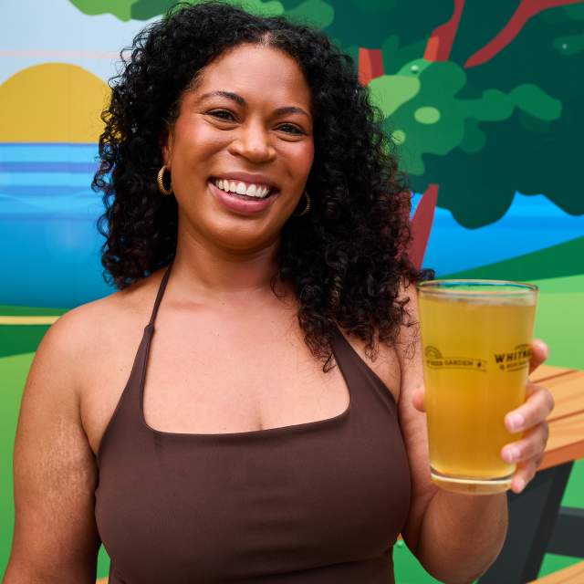 A woman smiling holding a beer at the Juneau Beer Garden