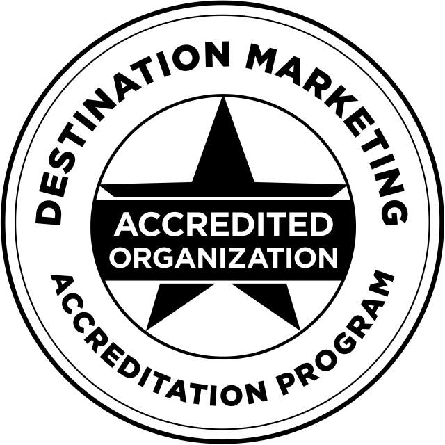 Black illustration of a star in the middle of a circle, with "Destination Marketing" in bold text rounded along the top of the circle, and "Accreditation Program" rounded along the bottom, with "Accredited Organization" across a banner overlapping the star in the middle.