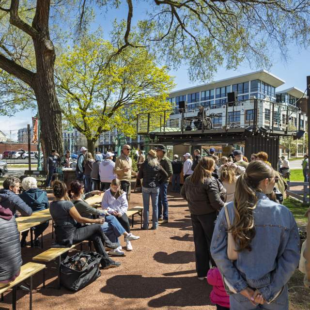 A large group of people sit and stand at a Third Ward Beer Garden, enjoying conversation and beer.