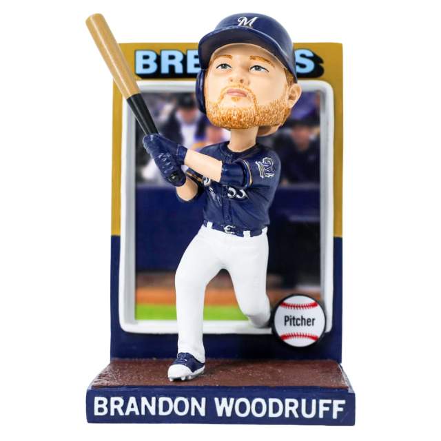A bobblehead figurine of a Milwaukee Brewers player wearing a navy jersey and helmet with a white “M,” holding a baseball bat in a batting stance. The base reads “Brandon Woodruff,” and a small baseball graphic labeled “Pitcher” appears beside him.