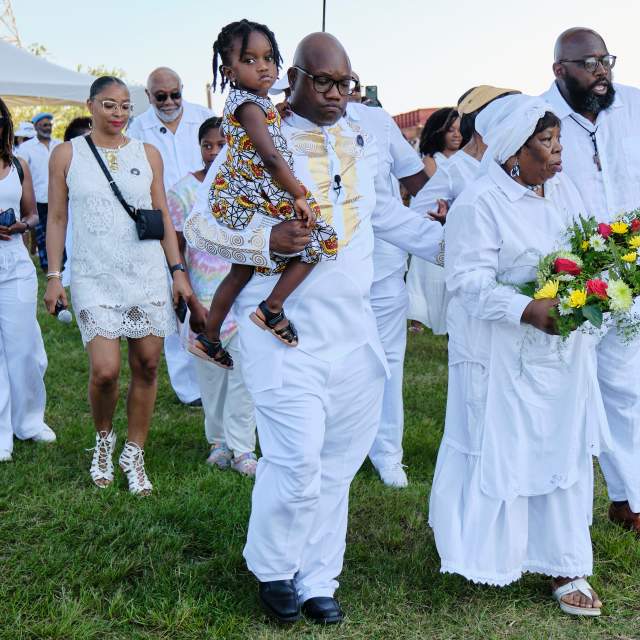 Group of African Americans in white clothing holding flowers and marching