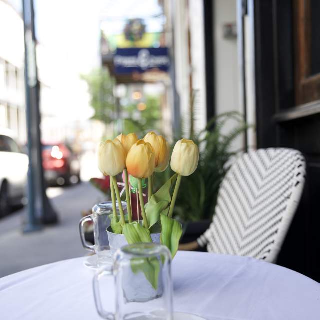 table and chair with a vase of tulips, outside dining