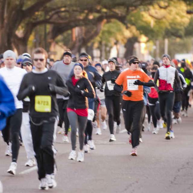 group of people running down the street in a race