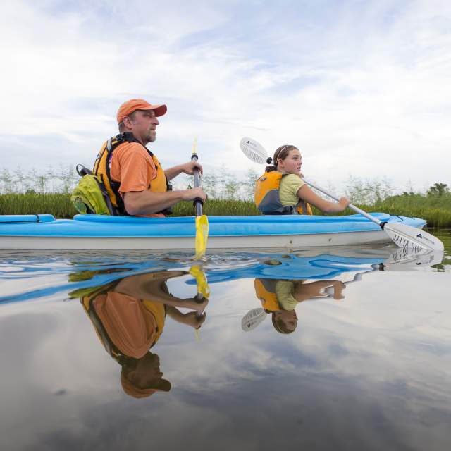 man and young girl kayaking in a blue kayak