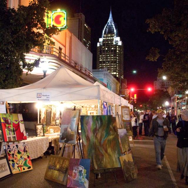 people walking down the street at night looking at art