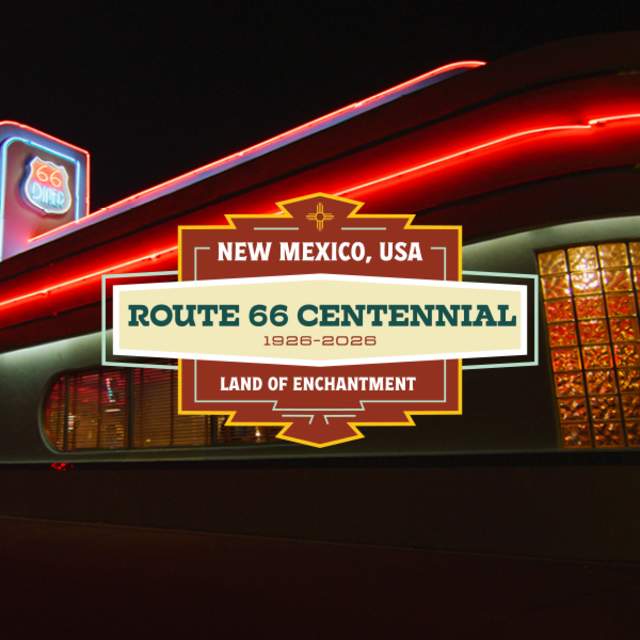 Nighttime view of a retro-style diner celebrating the Route 66 Centennial, with neon lights and the sign reading 'New Mexico, USA - Route 66 Centennial 1926-2026 - Land of Enchantment'.