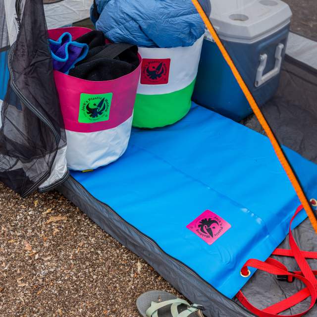 Camping gear inside a tent, a blue sleeping bag, a cooler, a blue mat, and a pair of sandals