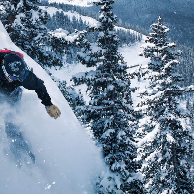 A snowboarder barrels down a steep hill at a New Mexico ski resort.