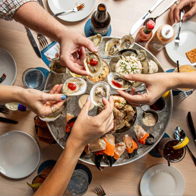 Friends share raw oysters, crab, and other chilled seafood as part of the seafood Plateau at Delacroix
