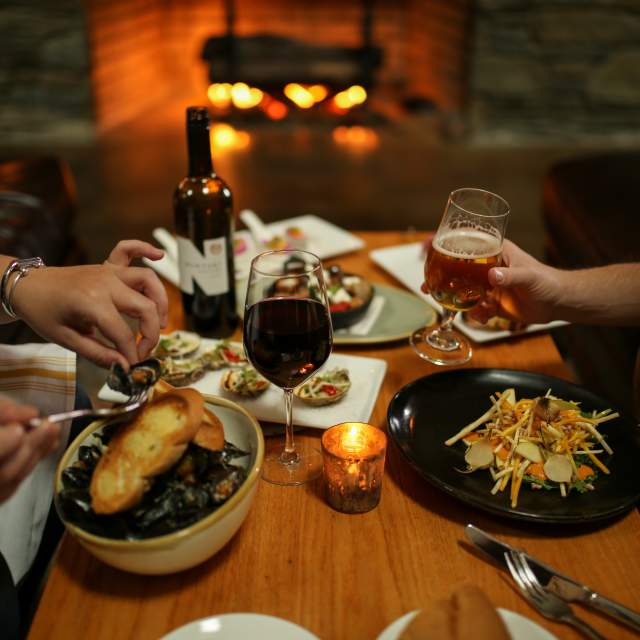 a dining table with food and drinks in front of a fireplace