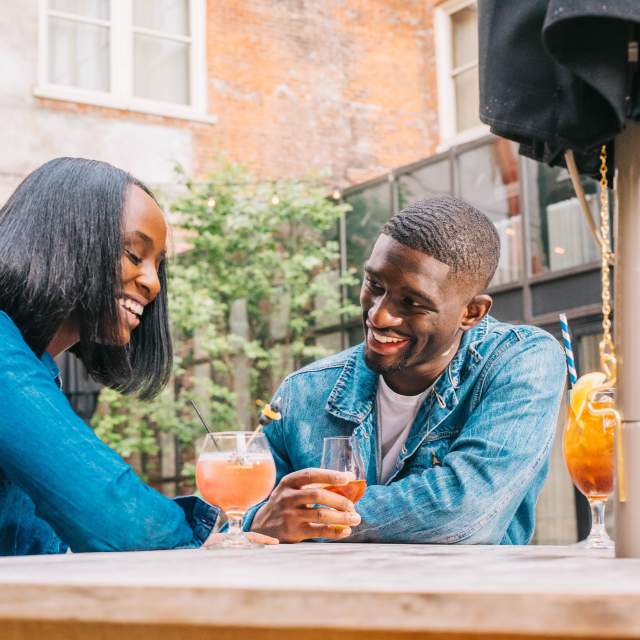 Young Black couple smiling at a table on the patio of Coppin's Restaurant at the Hotel Covington
