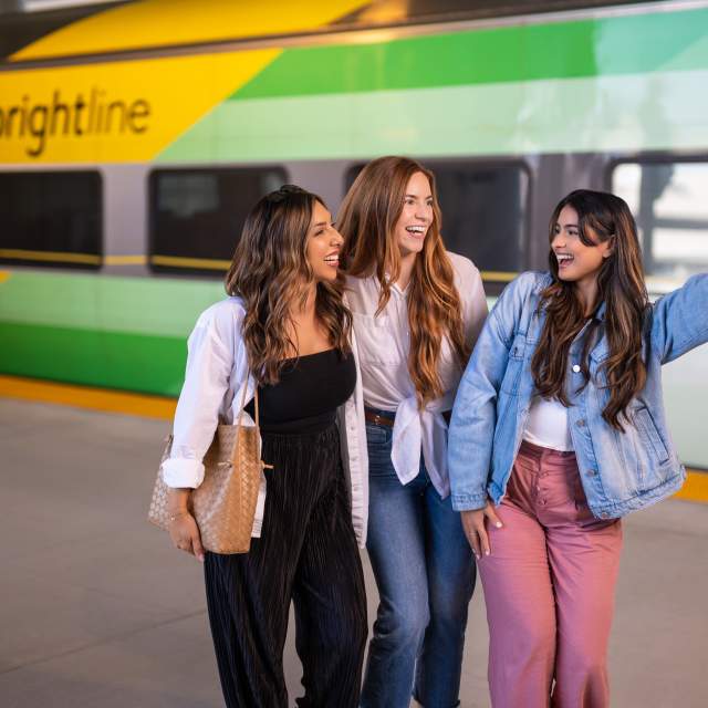 001 - Family walking though Brightline Terminal | 021 - Couple descending escalators to Brightline train platform | 013 - 3 Ladies posing for a selfie in front of Brightline train