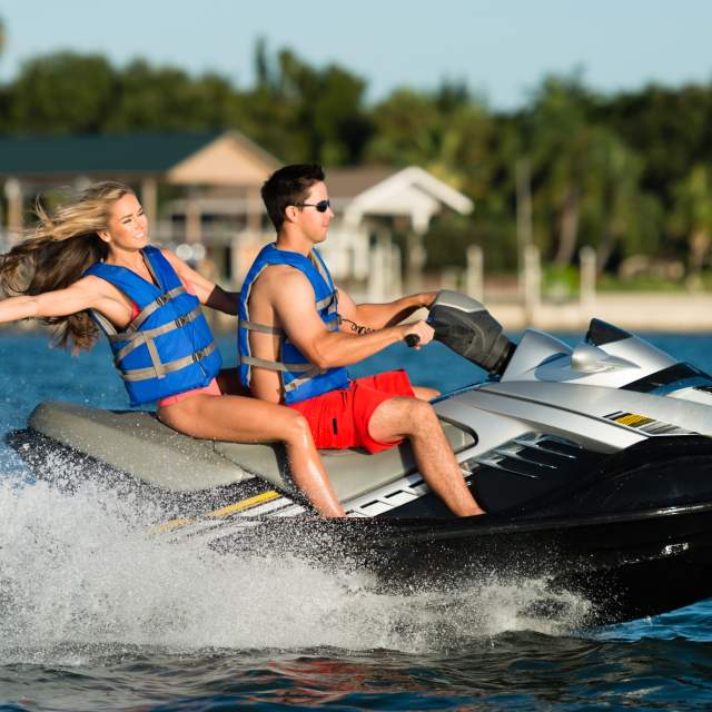 Attractive couple riding a waverunner personal water craft