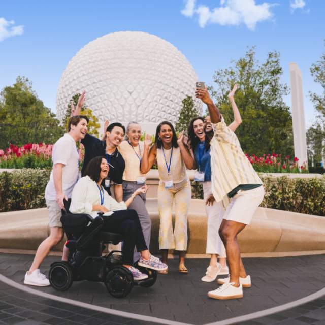 A group of meeting attendees at Epcot pose for a selfie.