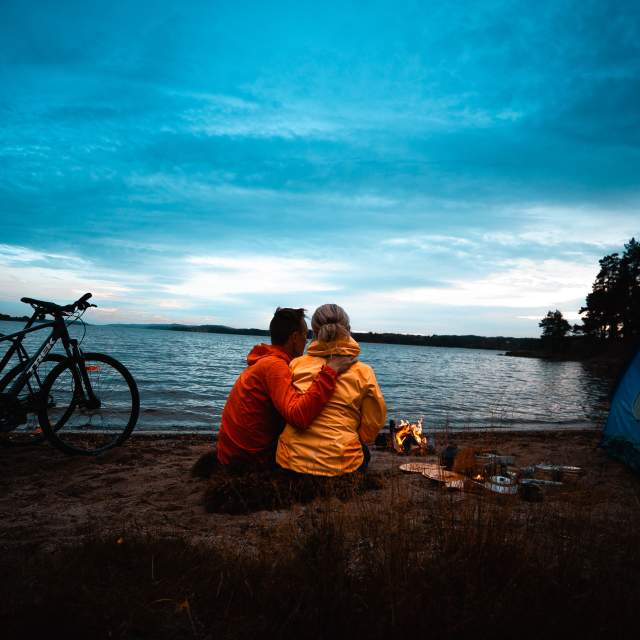Mann og kvinne på sykkel- og campingtur ved stranda