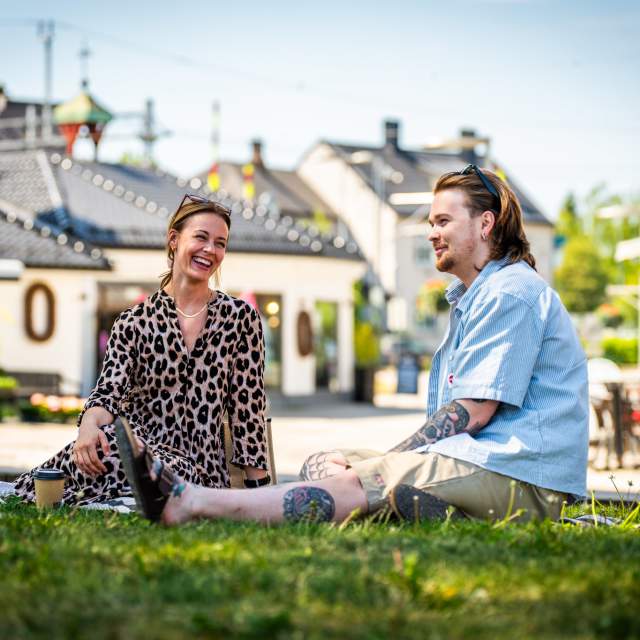 Ett par har piknikk i parken langs gågata