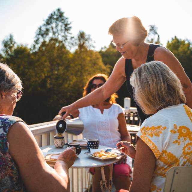 Tre damer får kaffe servert av Anne på Møllerens hus