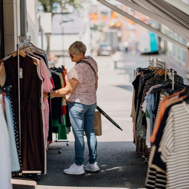 En dame som ser på klær utenfor en butikk