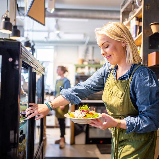 En ung dame tar ut en salatbolle fra disken