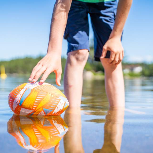 Mann holder badeball i vannoverflaten på stranda i Tangen i Ørje.