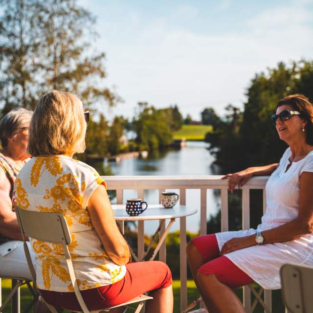Tre damer nyter en kaffepause i kveldssola i Strømsfossen, Aremark