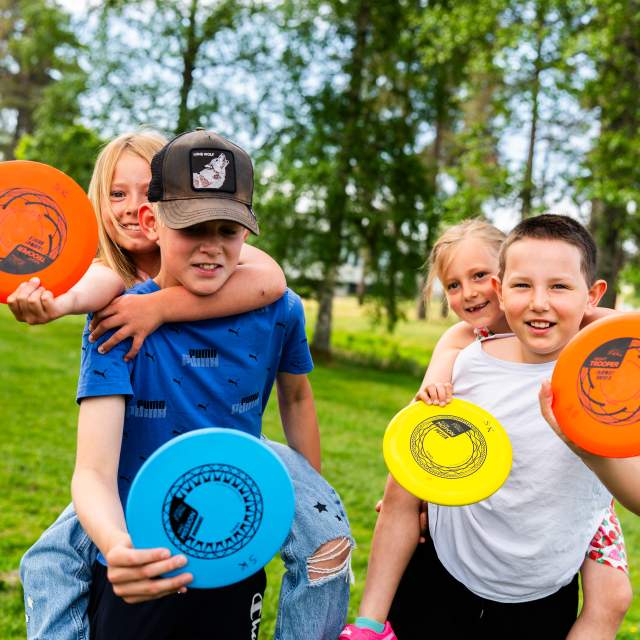 Fire barn som holder frisbee og sitter på ryggen til hverandre