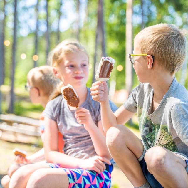 Tre barn sitter og spiser is